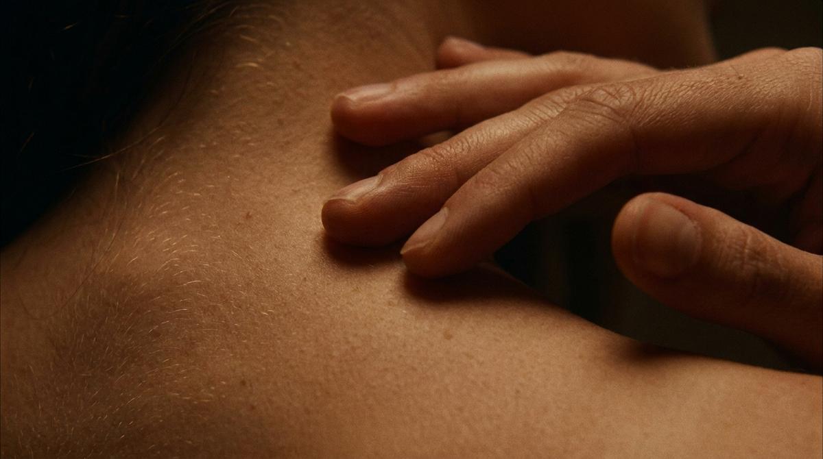 Fotografía macro mostrando el roce delicado de los dedos sobre la piel del cuello y la nuca
